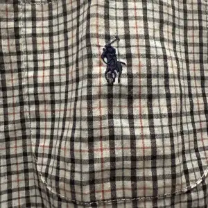 Säljer en klassisk rutig skjorta från Polo i 100% bomull. Skjortan har en broderad logga på bröstet och knappar framtill. Perfekt för en stilren look.