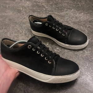 Lanvin - Snygga  svarta  lanvin sneakers med vit sula och snörning. Perfekta för en avslappnad stil. Skorna har en klassisk design med rund tå och är tillverkade i syntetmaterial. Uk 8 Passar 42 43 Gått upp jätte lite under inget som märks liten bit där fram har släppt Endast dustbag och skor följes med 