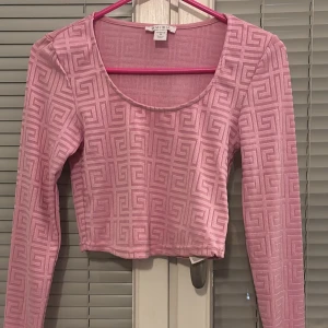 Rosa mönstrad topp från new yorker - Säljer en rosa långärmad topp från new yorker med ett geometriskt mönster. Toppen är croppad och har en rund halsringning. Perfekt för att ge en färgklick till din outfit!