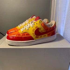 Färgglada Nike sneakers - Säljer ett par unika Nike sneakers i en färgglad design med röd, gul och orange färg. Skorna har en vit sula och klassisk snörning. Perfekta för dig som vill sticka ut med en färgsprakande stil. Egen design ❗️❗️❗️