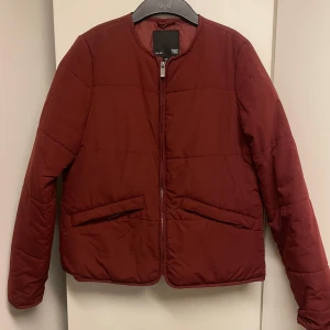 Vinröd pufferjacka från H&M - Säljer en snygg vinröd pufferjacka från H&M. Jackan har en dragkedja framtill och två praktiska fickor. Perfekt för kyligare dagar och ger en stilren look. Passar bra till både jeans och kjol. 🧥