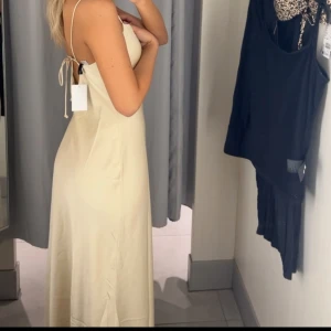 Champagnefärgad långklänning - Säljer denna fina klänning som jag hade på min mösspåtagning. Får en figursydd kropp i denna och materialet är sååå skönt. Endast använd en gång så i super bra skick. Passar perfekt på mig som är en S/M. Pris kan diskuteras.