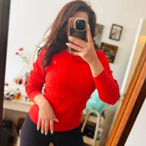 Röd stickad tröja från GANT - Säljer en superfin röd stickad tröja från GANT. Den har ett klassiskt kabelstickat mönster och är perfekt för både höst och vinter. Tröjan är långärmad och har en normal passform. Den är i nyskick och redo att bli en del av din garderob!