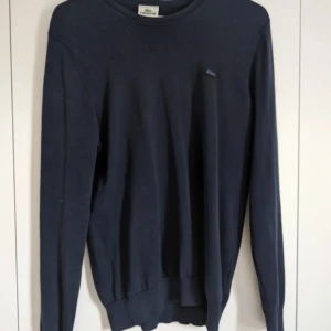 Stickad Lacoste tröja - En väldigt fet mörkblå stickad Lacoste tröja,  8/10 skick Skriv i DM för fler bilder eller om ni har några funderingar😁