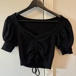 Svart topp med puffiga ärmar - Svart kortärmad topp med puffiga ärmar, ej använd
