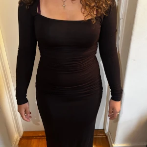 Svart långärmad klänning - Säljer en elegant svart långärmad klänning som är perfekt för festliga tillfällen. Klänningen har en tight passform som framhäver figuren och en stilren design. Den är gjord i ett mjukt och stretchigt material som gör den bekväm att bära hela kvällen.