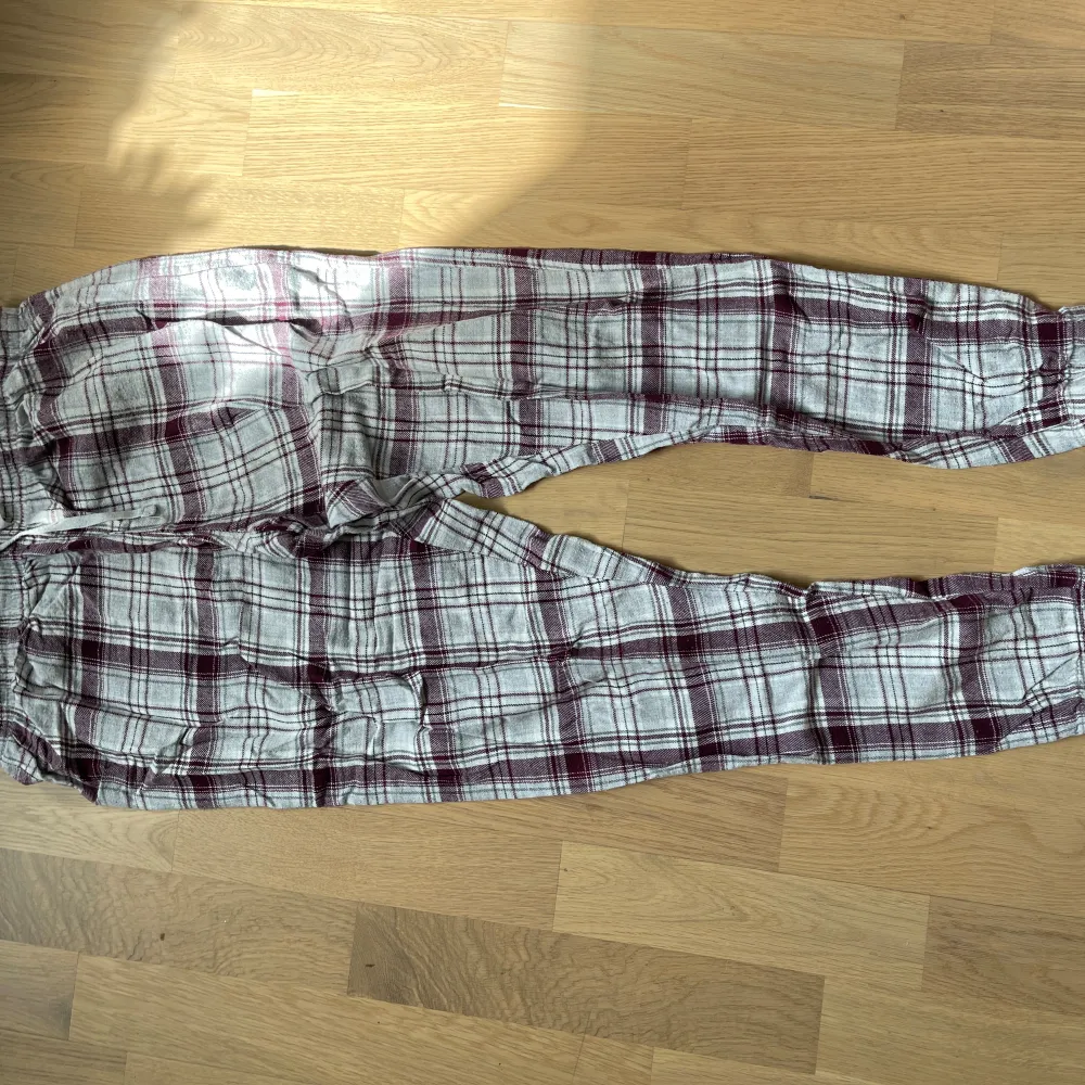 Säljer ett par supermysiga rutiga pyjamasbyxor i bomull. De är i en snygg kombination av lila och vitt, perfekt för en avslappnad dag hemma. Byxorna har en bekväm passform med resår i midjan och snörning för extra justering. Perfekta för höst- och vintermys!. Jeans & Byxor.