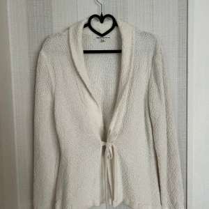 Vit kofta  - En vit kofta med långa ärmar och en krage. Den har en snörning i midjan. Kofta är i gott skick.