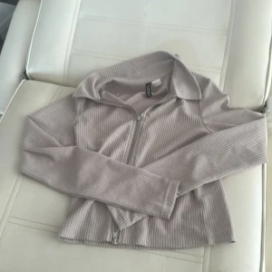 Beige ribbad tröja från H&M Divided - Säljer en superfin beige ribbad tröja från H&M Divided. Den har en dragkedja framtill och långa ärmar, perfekt för höst och vår. Tröjan är i storlek S och är i nyskick. Perfekt för en casual look eller att klä upp med accessoarer!🤍