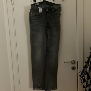 Grå Levis 501 jeans stl. 24/30 - Snygga grå Levis 501 jeans med klassisk design. De har en rak passform och är tillverkade i slitstarkt denim. Perfekta för en avslappnad stil. Jeansens ikoniska lädermärke syns tydligt på baksidan. Är använda endast 2 gånger 