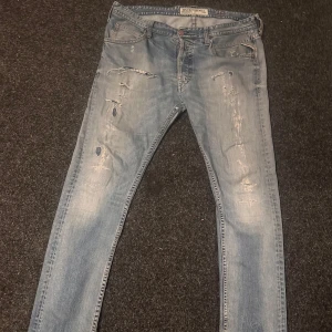 Blå jeans från Replay - Snygga blå jeans från Replay med slitna detaljer och en klassisk femficksdesign. De har en knappgylf och är perfekta för en avslappnad stil. Märket Replay syns tydligt på insidan av midjan. Priset är ej hugget i sten heller, för mer information är det bara att skriva bits inte!!😆😆