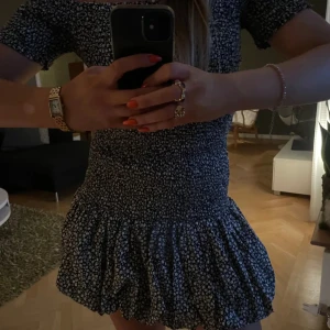 Blommig klänning med volang - Säljer en söt blommig klänning med volangdetaljer. Klänningen har korta ärmar och en smickrande passform. Perfekt för sommarens alla tillfällen!