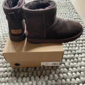 Bruna UGG Classic Mini II - Säljer ett par bruna UGG Classic Mini II boots i mocka. De är perfekta för kyliga dagar med sin mjuka och varma insida. Den klassiska designen gör dem lätta att matcha med olika outfits. Chokladbruna, strl 36 fint skick, använda enstaka gånger Nypris, ca 2200kr 
