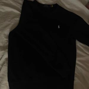 Mörk Blå tröja från Ralph Lauren - Säljer en stilren blå tröja från Ralph Lauren med det klassiska broderade logotypen på bröstet. Tröjan har en enkel design och är perfekt för en avslappnad stil. Pris är diskuterbart. 