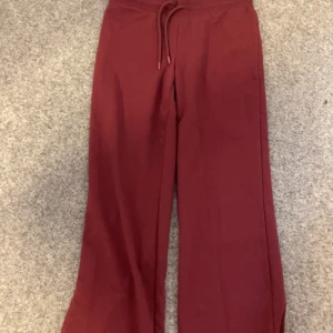 Vinröda byxor med dragsko - Snygga vinröda byxor med dragsko i midjan. Byxorna har en loose passform och är perfekta för en avslappnad stil. De är tillverkade i ett mjukt material som ger en bekväm känsla hela dagen.