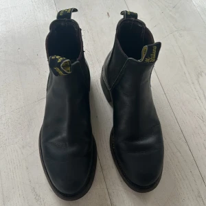 Svarta boots från R.M. Williams - Snygga svarta boots från R.M. Williams i skinn. De har en klassisk design med elastiska paneler på sidorna och en robust sula. Perfekta för en stilren look.