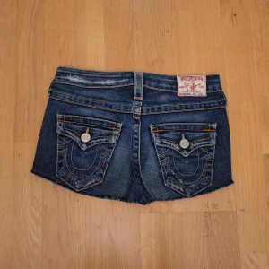 True Religion jeanskjol - Säljer en jätte snygg jeanskjol från True Religion. Den är mörkblå med slitna detaljer och har dekorativa sömmar. Kjolen har låg midja och knappar fram. Perfekta för en avslappnad stil! Skriv vid frågor och prisförslag💕