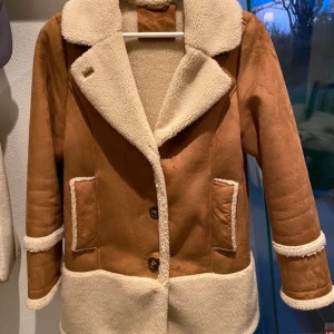 Brun mockajacka med pälsfoder - Säljer en snygg brun mockajacka med mjukt pälsfoder. Jackan har stora knappar framtill och två praktiska fickor. 