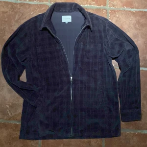 Mörkblå overshirt från Vailent - Säljer en snygg mörkblå overshirt från Vailent i 100% bomull. Den har ett diskret rutmönster och dragkedja framtill. Perfekt för lager-på-lager-stil. Långärmad med klassisk krage. Kan diskutera priset 