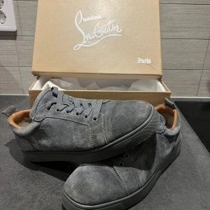  Christian Louboutin skor - Snygga grå sneakers från Christian Louboutin i mocka med den ikoniska röda sulan. Skorna har snörning och en stilren design som passar perfekt för en trendig look. Allt og ingår. Pris går att diskutera vid snabb affär. 