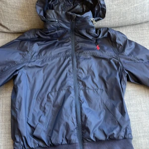 Ralph Lauren Regnjacka 10-12y - As snygg regnjacka köpt för runt 1000kr man kan både ha med luva eller inte luva passar året runt förutom vintern perfekt nu för hösten. Säljer för att den är förliten den passar 140-154 ungefär 