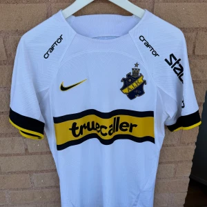 AIK tröja - Nyskick utan prislapp, endast testad av mig. Den passade tyvärr inte och har rört bort kvittot. Bortaställ från denna sässong 2024. Spara en slant och köp denna istället för nytt, nypris 1299 i AIK shoppen!