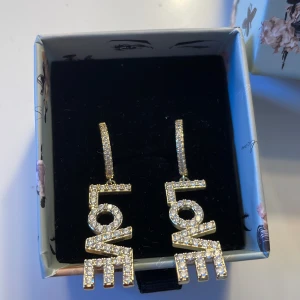 IOAKU örhängen  - Säljer mina jätte fina ioaku örhängen med ordet love då den inte kommer till andvänding dem är i nyskicks och knappt använda 