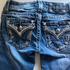 Miss Me Jeans - Strl 7, motsvarandena strl 140. 28 cm midja rakt över. 61 cm innersöm. Bootcut. Fint skick. Endast en Sten som saknas på bakfickan. Se bild.