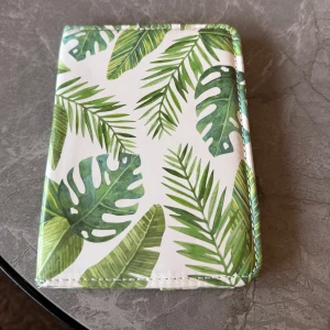 Tropisk mönstrad passfodral - Snyggt passfodral med tropiskt bladmotiv i grönt och vitt. Perfekt för att skydda sitt pass. Den har ett fräscht och somrigt utseende som sticker ut.