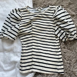 Randig topp med volanger - Svart och benvit ish, är en någorlunda annorlunda vit färg/material på ärmarna, men inget man tänker på avstånd. 