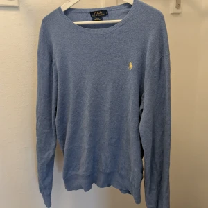 Blå tröja från Ralph Lauren - Säljer en stilren blå tröja från Ralph Lauren i slim fit. Tröjan är tillverkad av mjuk pima bomull och har en broderad logotyp på bröstet. Perfekt för en avslappnad men ändå elegant look.