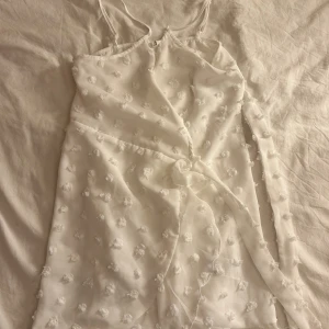 Vit  klänning med mönster och band  - Söt vit klänning med smala axelband. Perfekt för sommarens varma dagar. Klänningen har en knytning i midjan för en fin passform. jätte skönt material. aldrig använd 