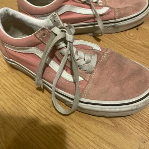 Rosa sneakers från Vans - Säljer ett par rosa Vans sneakers med vit sula och snörning. Skorna har en klassisk design med den ikoniska sidostripen i vitt. Perfekta för en avslappnad stil. Det syns att det är använda då de är smutsiga men annars är det helt användbara utan några skador!