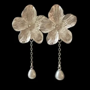 Silverfärgade blomörhängen med pärldetalj - Priset avser ett par örhängen. Eleganta örhängen i form av blommor med en hängande kedja och pärldetalj. Perfekta för att ge en stilfull touch till din look.