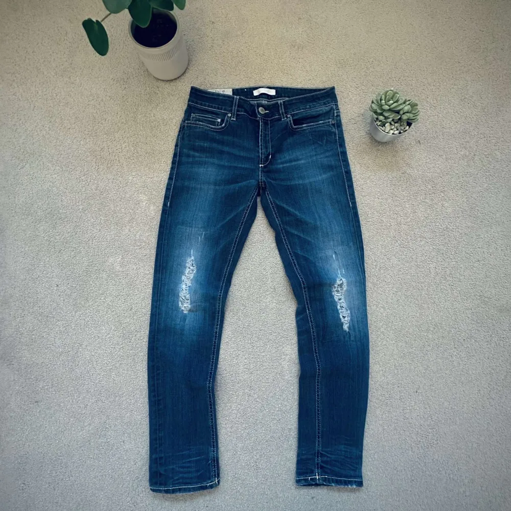 Snygga blå jeans från Dondup med slitna detaljer på framsidan. De har en klassisk femficksdesign och en läderpatch med logotyp på baksidan. Perfekta för en avslappnad stil. Ny pris 2300. Passar cirka 165/172. Är i slim fit. Farkut & Housut.