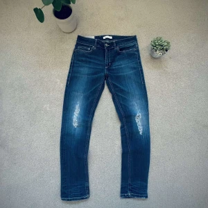 Blå jeans från Dondup - Snygga blå jeans från Dondup med slitna detaljer på framsidan. De har en klassisk femficksdesign och en läderpatch med logotyp på baksidan. Perfekta för en avslappnad stil. Ny pris 2300. Passar cirka 165/172. Är i slim fit
