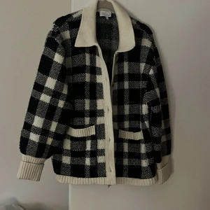 Svartvit rutig kofta från & Other Stories - Säljer en snygg svartvit rutig kofta från & Other Stories. Jackan har en klassisk krage och knappar framtill. Den är långärmad med ribbade muddar och har två fickor fram.