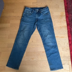 Blå jeans från H&M - Säljer ett par klassiska blå jeans från H&M i straight regular fit. De har en traditionell femficksdesign och är tillverkade i denim. Perfekta för en avslappnad stil. OBS har ett litet håll längst ner vid vänstra byxan. Kan diskutera om priset 