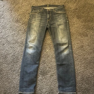 Blå jeans från Lee - Snygga blå jeans från Lee med klassisk femficksdesign och en bekväm passform. De har en lätt tvättad look och är perfekta för en avslappnad stil. Märkeslogga på baksidan av midjan.