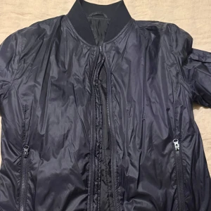 Svart bomberjacka från Filippa K - Snygg svart bomberjacka från Filippa K med dragkedja framtill och ribbad krage. Jackan har en stilren design med praktiska fickor och är perfekt för en cool look. Skicket är 10/10. PM för mer info. 