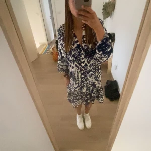 Mönstrad klänning i blått och vitt - Säljer en snygg klänning med ett unikt blått och vitt mönster. Klänningen har en v-ringad design och trekvartsärmar, perfekt för både vår och sommar. Den har en avslappnad passform som ger en bekväm känsla. Använd en gång men slängde lappen så kunde inte lämna tillbaka. Bara att skriva för fler bilder ❣️