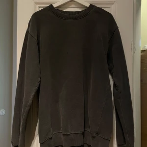 Mörkgrå sweatshirt - Säljer en stilren mörkgrå sweatshirt med rund hals och långa ärmar. Perfekt för en avslappnad look. Tröjan har ribbade muddar vid ärmslut och nederkant.