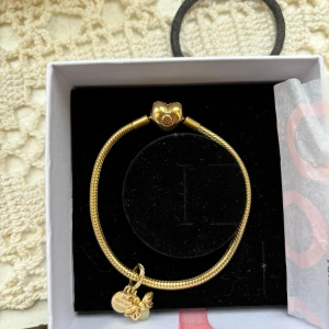 Guldarmband från Pandora med hängsmycken -  Säljer nu min jättefin pandora armband med belocket i guld är i jättefin skick i storlek 18cm, belocket lyser i mörkret, spännet på armbandet är hårt det kan vara lite svårt att öppna och stänga men man lär sig, lådan till armbandet följer med, skriv i chatten om ni har några frågor❤️ Nypris: 2498kr