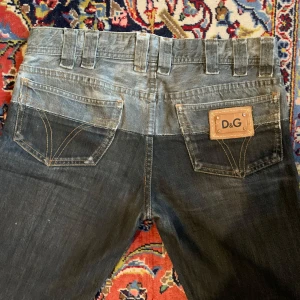 Svarta jeansbyxor från D&G - Snygga svarta jeansbyxor från D&G med en cool tvättad look. Byxorna har en klassisk femficksdesign och en läderpatch med D&G-logga på bakfickan. De har en knappgylf och bälteshällor för en perfekt passform. Innebenslängd 86cm