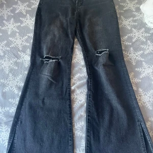 Svarta bootcut jeans med slitningar - Snygga svarta bootcut jeans med slitningar på knäna och slits ner på byxan utåt. Etiketten är avklippt då den rev, men tvättas i 30 grader. Perekt för en avslappnad stil.  