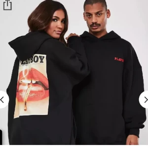 Svart hoodie med Playboy-tryck - Säljer en svart hoodie från Playboy med ett coolt tryck av röda läppar och en tänd cigarett på ryggen. Framtill finns en liten röd text med 'PLAYBOY'. Perfekt för en avslappnad stil eller en utekväll. Superbekväm och i bra skick! Den är ganska oversized, även om det är storlek 32, UK 4. 