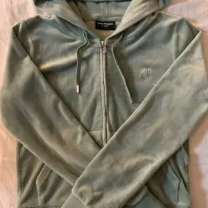 Mysig mintgrön hoodie från Juicy Couture. Den har en dragkedja framtill och en praktisk huva med snören. Som ni ser på bild 2 så e den ena metall biten tyvärr sönder på ena snöret därav priset. Nypris 1200.