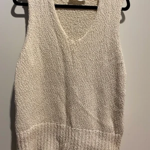 Vit stickad väst från Elvine - Säljer en stilren vit stickad väst från Elvine i storlek M. Västen har en v-ringad design och är perfekt för lager-på-lager under höst och vår. Den är i mycket bra skick och passar både till vardags och festligare tillfällen. Köpt ny för 800kr 