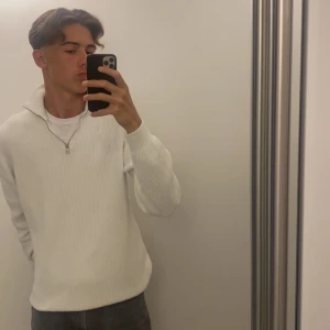 Vit stickad tröja från Zara - Säljer en stilren vit stickad tröja från Zara i storlek M. Tröjan har en dragkedja vid halsen och är perfekt för både höst och vinter. Den är i mycket bra skick och passar till alla tillfällen. Perfekt för dig som vill ha en enkel men snygg look! 