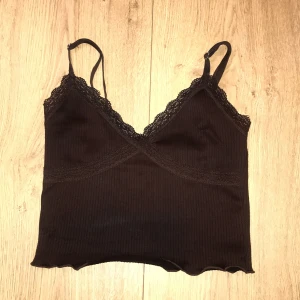 Brun ribbad linnetopp från H&M Divided - Säljer en superfin brun ribbad linnetopp från H&M Divided. Den har justerbara axelband och vacker spetsdetalj vid urringningen. Perfekt för både vardag och fest! 🧡